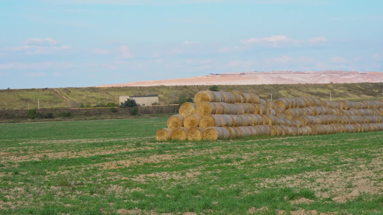 稻草堆成金字塔。收获的土地与包，小麦收获的面包生产。农田里的草捆，蓝天白云。相机从左到右视频下载