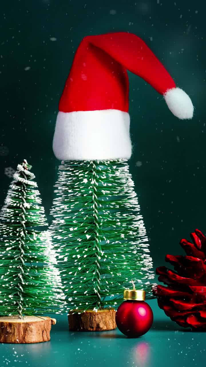 圣诞快乐和新年快乐雪花飘落与ed圣诞帽在绿色松树在深绿色背景。节日庆祝贺卡视频素材