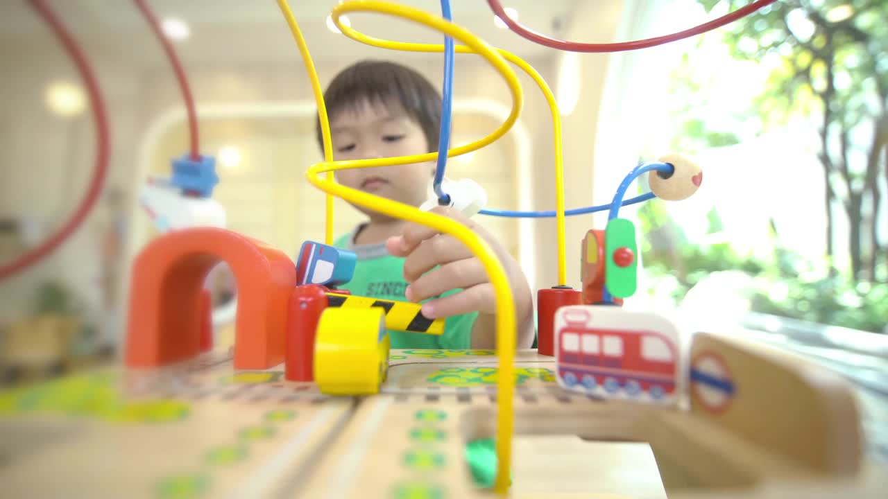 蹒跚学步的男孩在游戏室里玩算盘，学习数学玩具视频素材