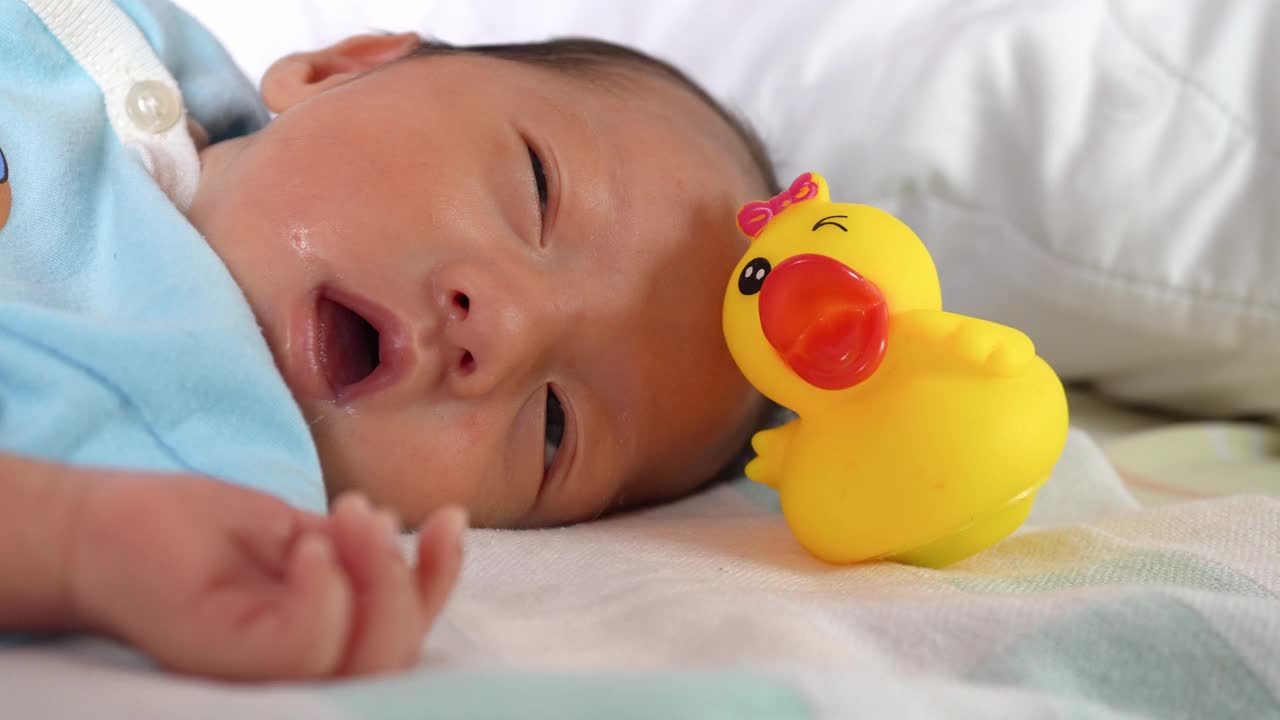 刚出生的小男孩和黄色的橡皮鸭一起睡觉视频素材