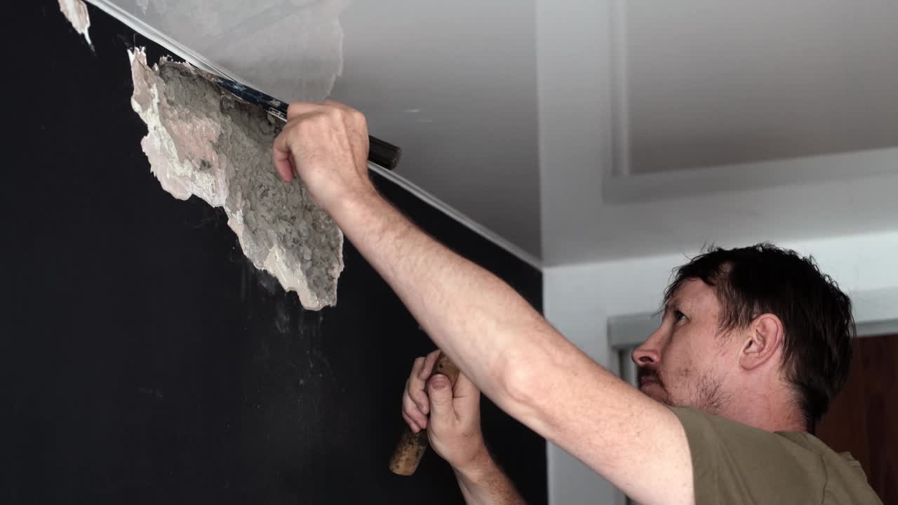 人在家里修理，并用锤子和凿子破坏混凝土墙。慢动作视频素材