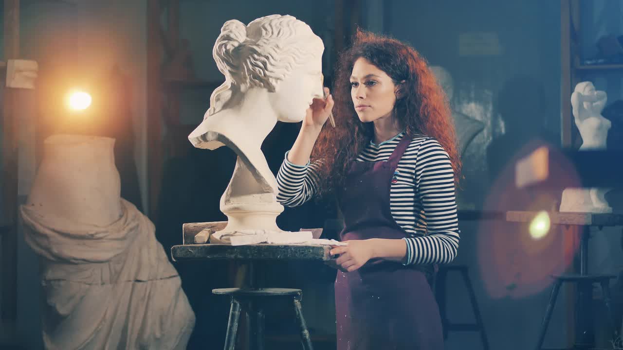 一位女艺术家正在仔细地刷一件石膏雕塑。创意，灵感，想象。视频下载