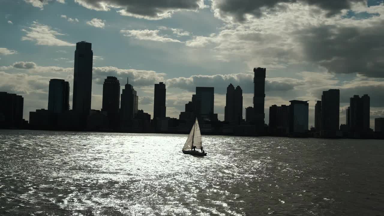 一艘帆船在城市的背景下航行，日落时分的纽约曼哈顿。视频素材