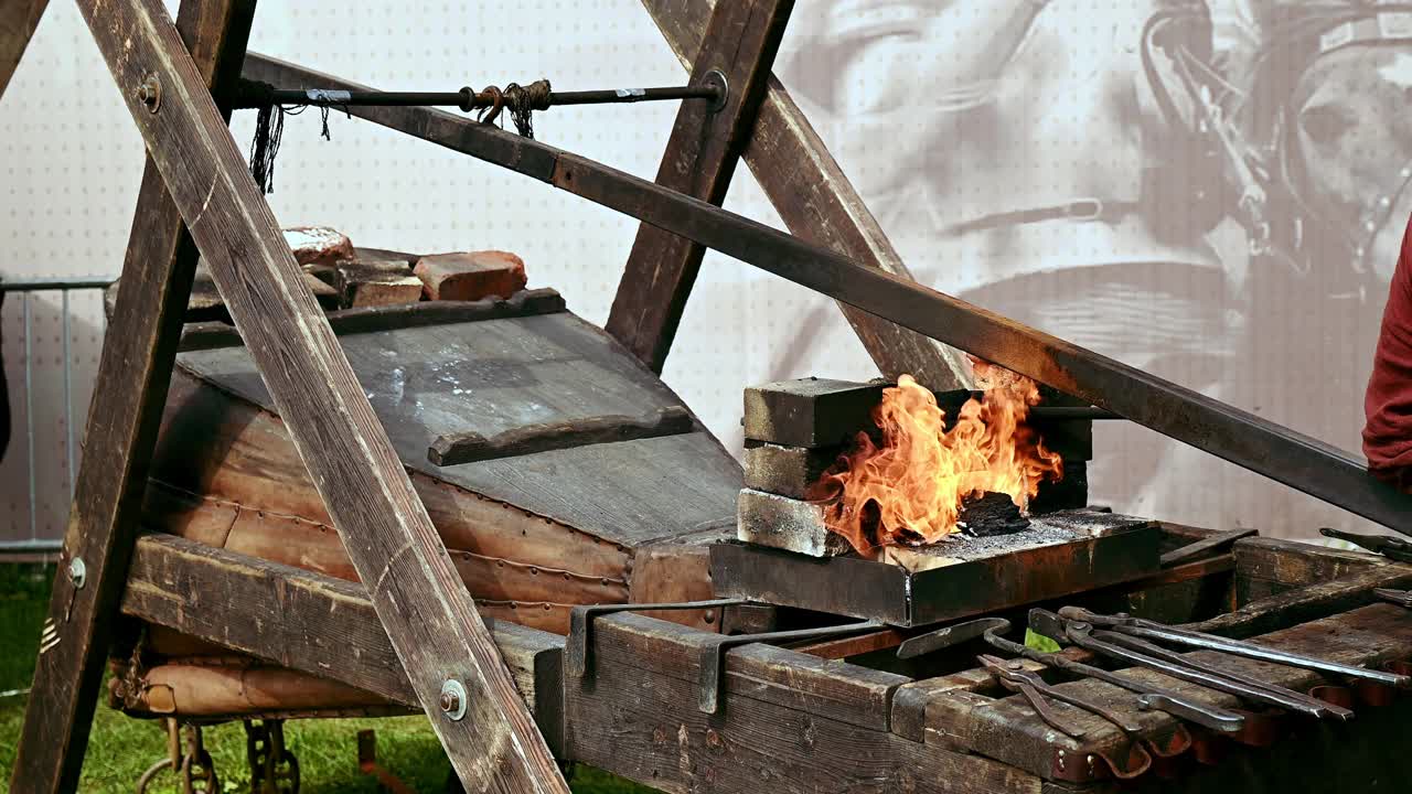 铁匠将火盆的风箱充气，用钳子将炽热的金属部分从火中取出视频下载