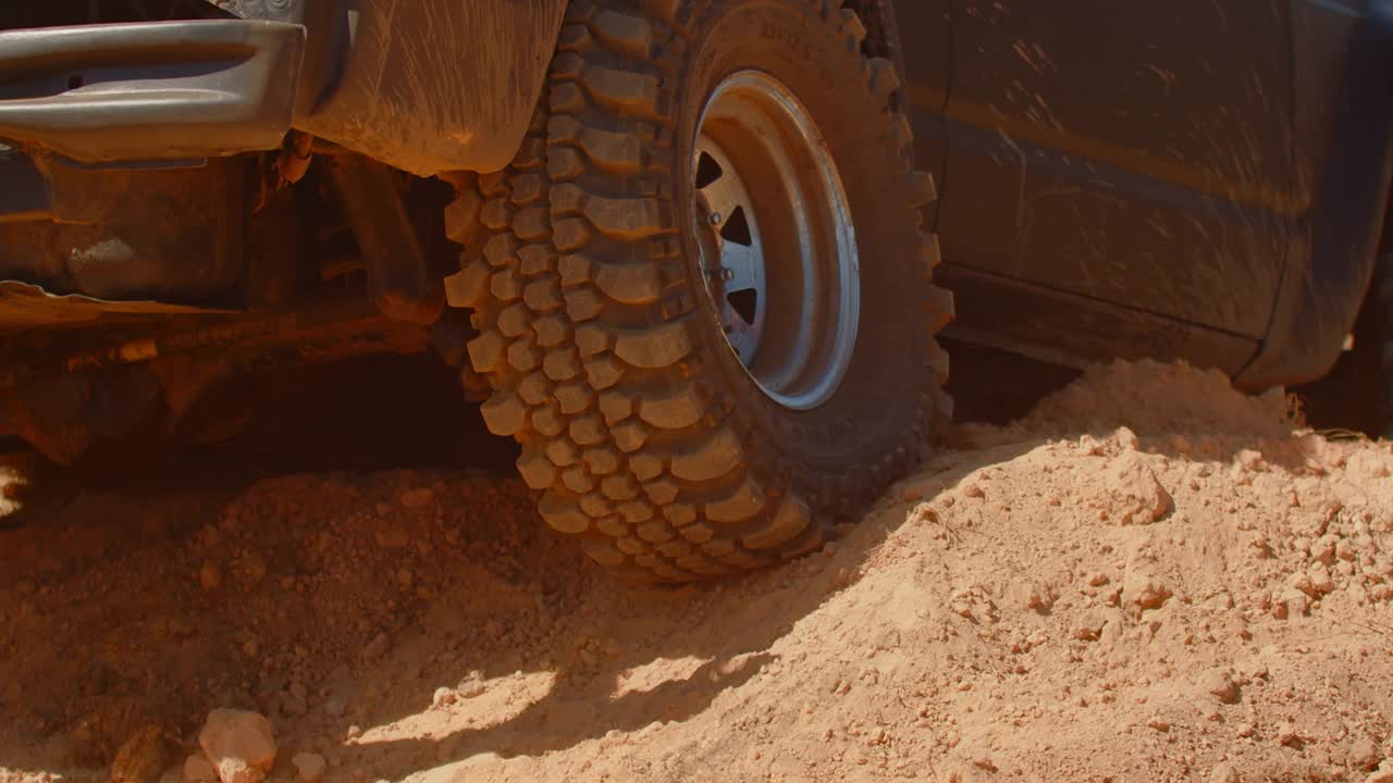 轿车行驶在沙质道路上，尘土飞扬，后视图。慢镜头，轮子的特写镜头。强大的越野车的概念视频素材