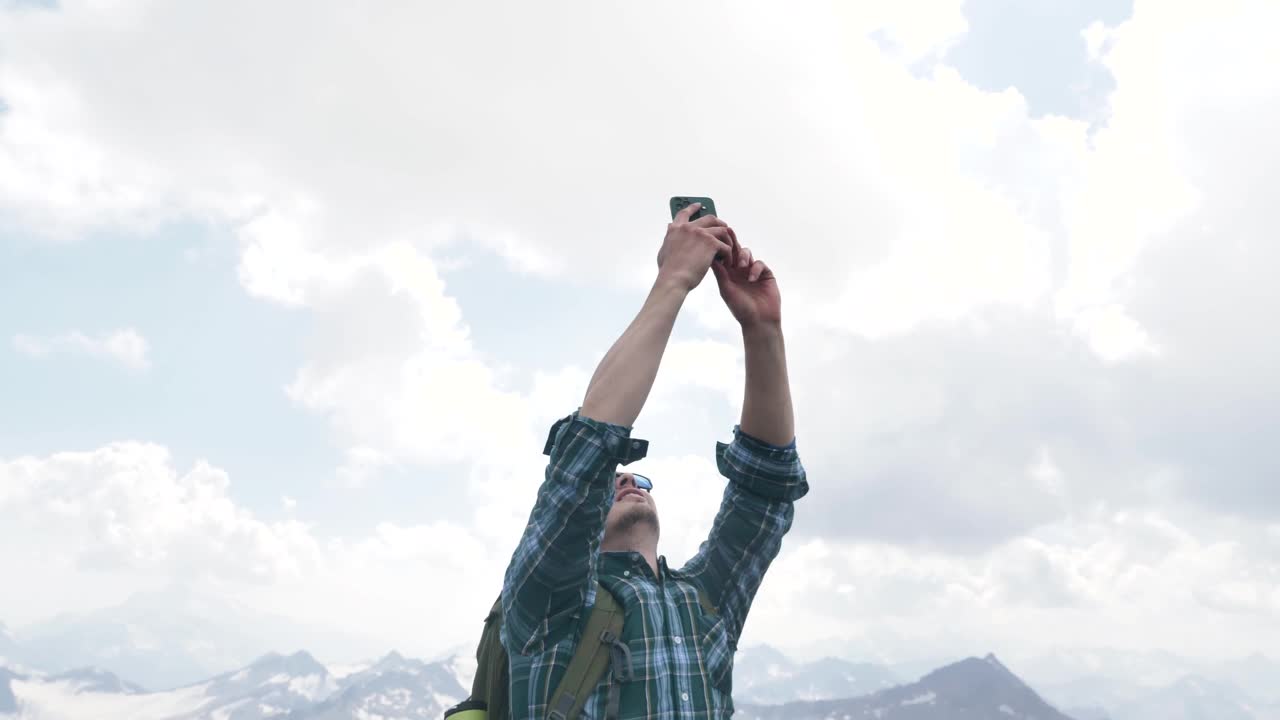 戴着太阳镜的男性游客在山里用手机连接或上网视频素材