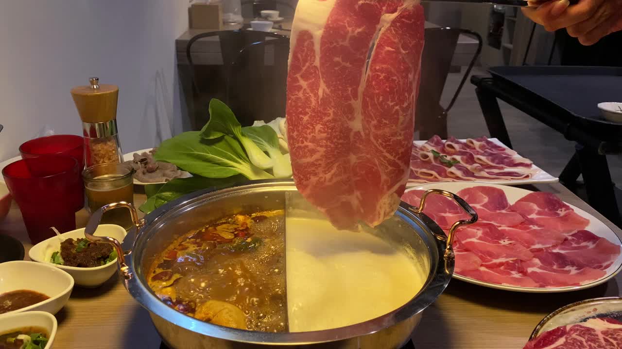 生牛肉用筷子夹住。中国的铜锅火锅视频素材