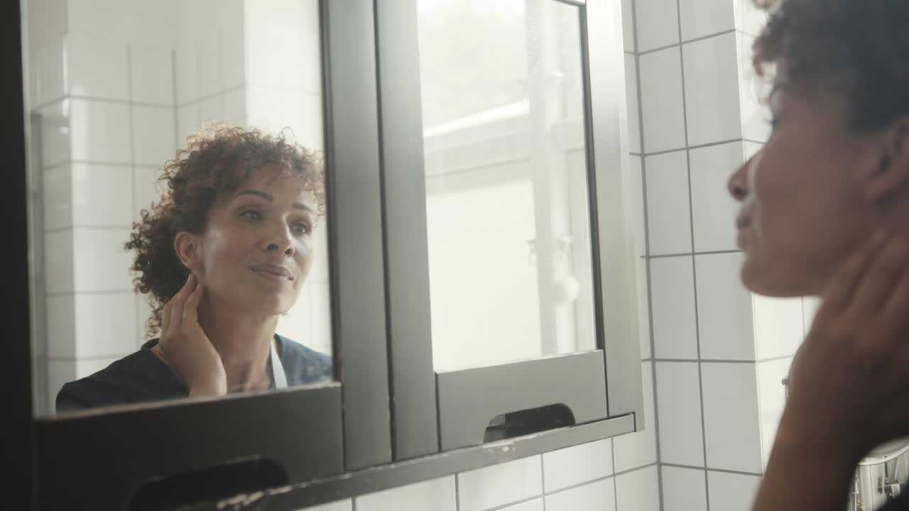 一个女人在浴室镜子里看着自己的脸视频下载