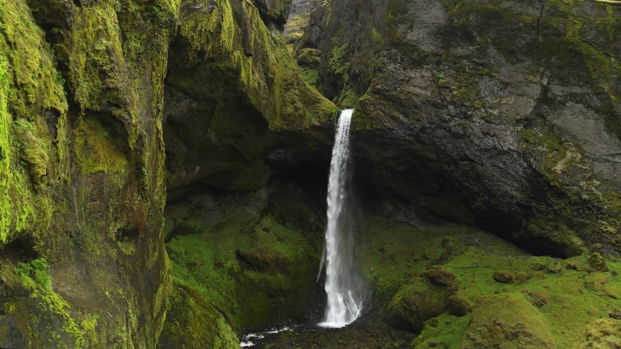 在冰岛的赫沃斯韦利，空中飞过绿色悬崖的瀑布视频下载