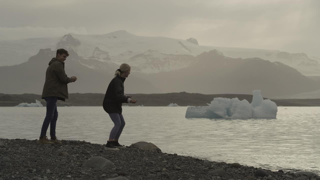 在冰岛的Jokulsarlon泻湖，一对夫妇在水中玩石子视频下载