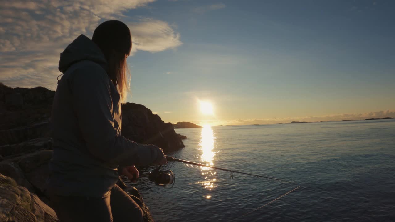 女人在海边用鱼竿纺线钓鱼，钓到一条鳕鱼视频下载