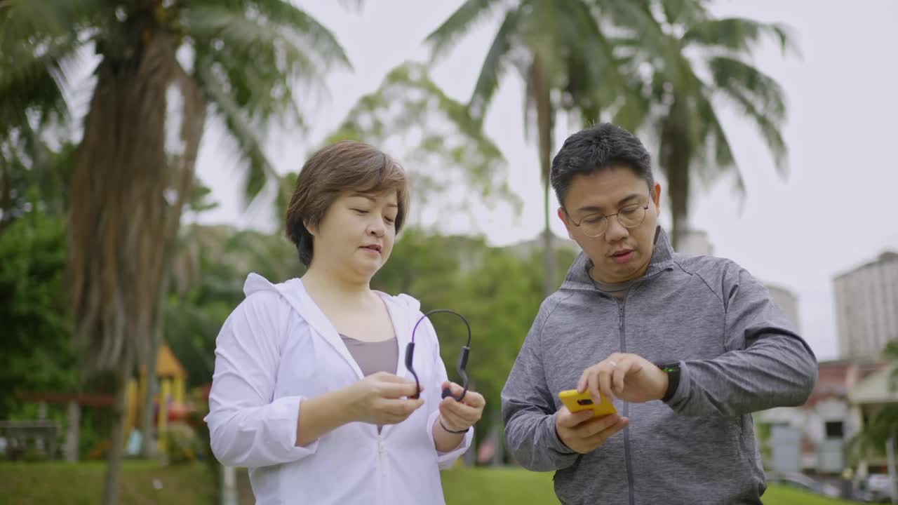 亚洲华人中年夫妇穿着运动服跑着微笑着看向公园视频素材