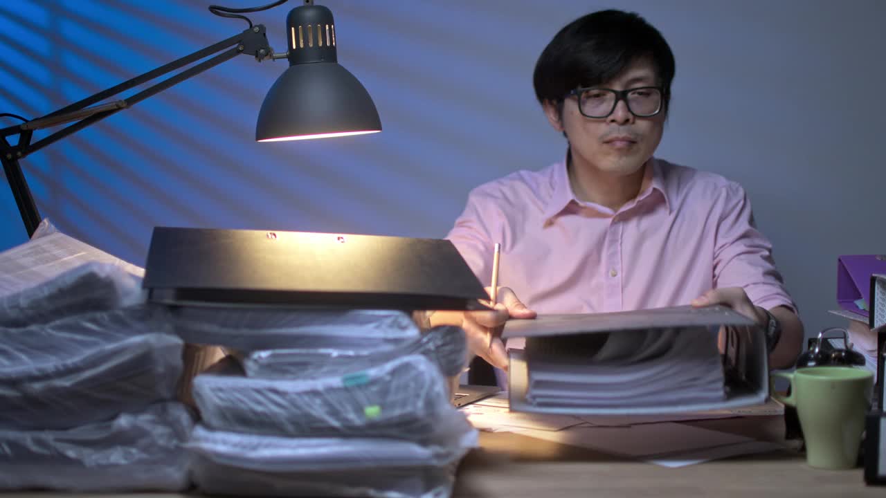 亚洲商人在加班时打开文件夹查看文件。努力完成项目。视频素材