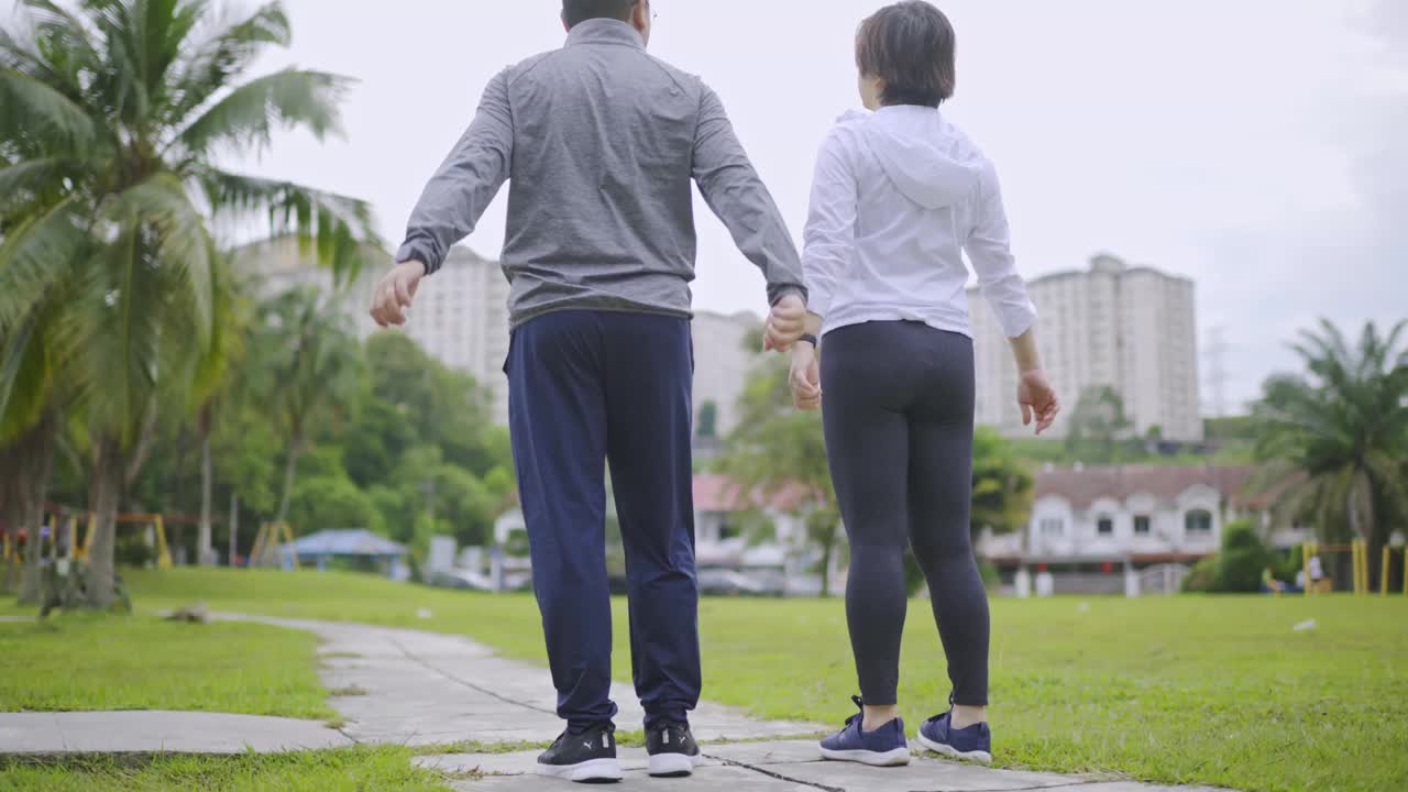 后视图亚洲中国中年夫妇与运动运动服跑步微笑看着远处的公园视频素材