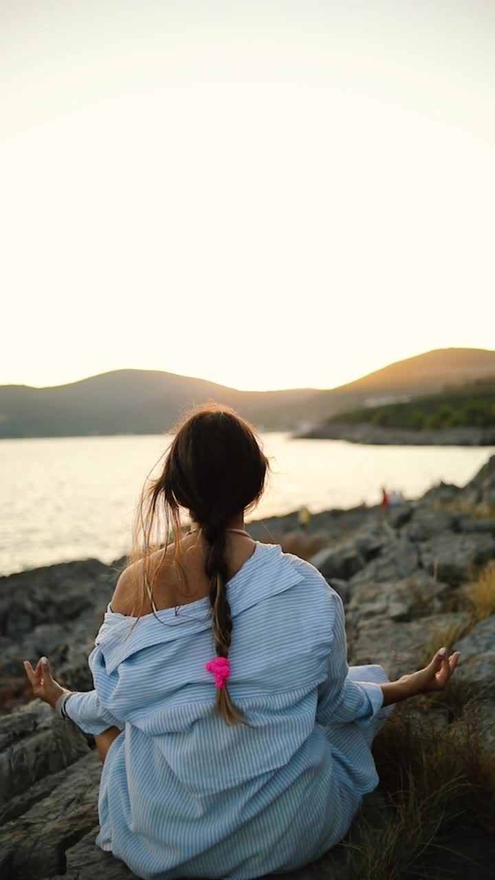 海边的一个年轻女子正在做瑜伽和冥想视频下载