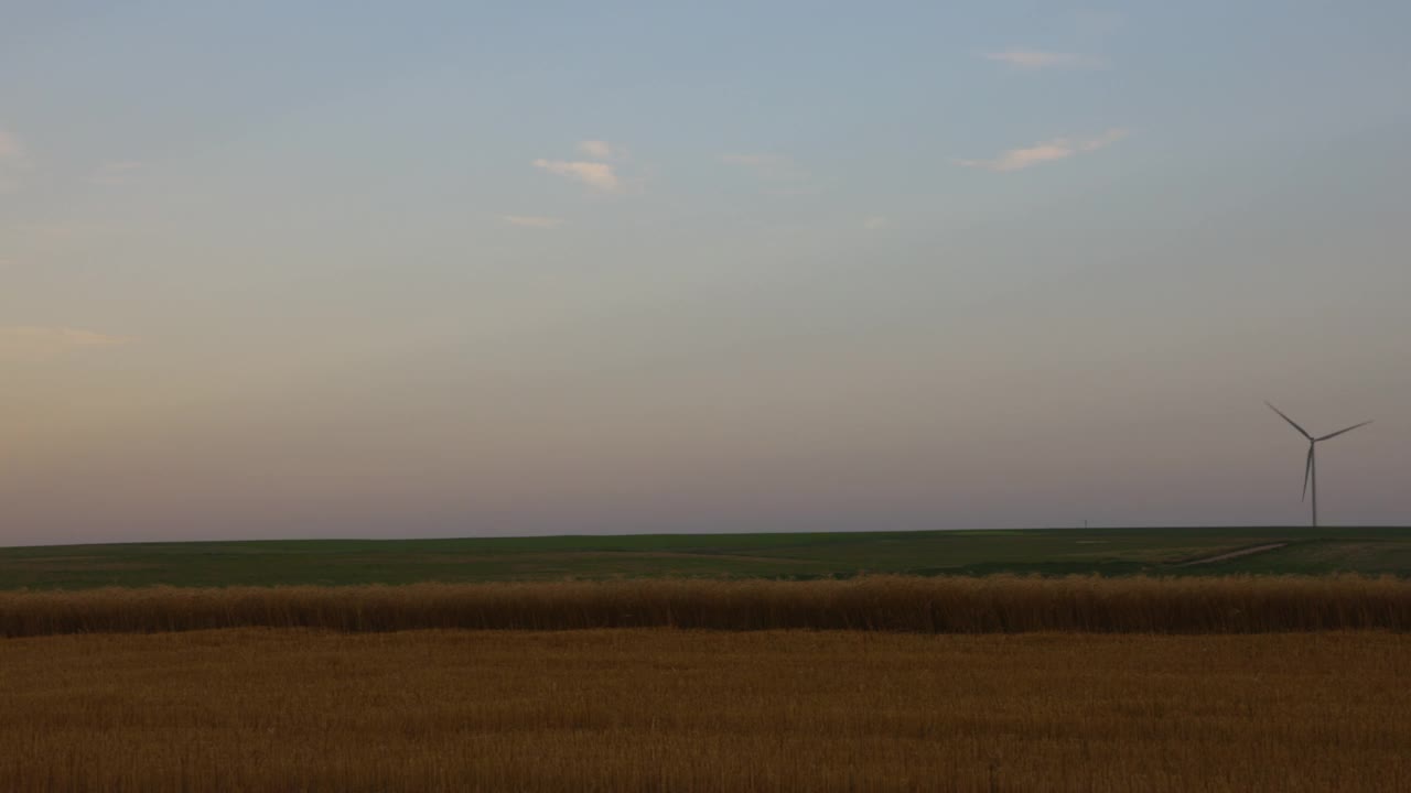 夏季日落时，麦田里风力涡轮机的极宽镜头视频下载