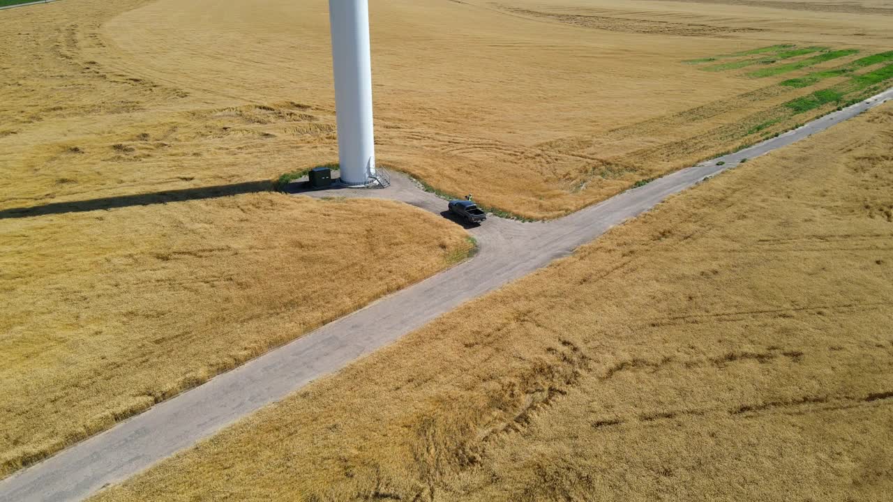 夏季下午，工程师在麦田里检查风力发电机的空中小车前摄视频下载