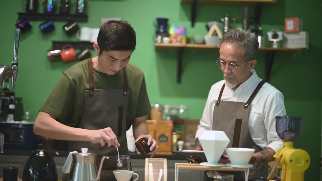 亚洲华人男咖啡师咖啡店老板正在和他的员工进行冷煮咖啡点滴培训视频素材