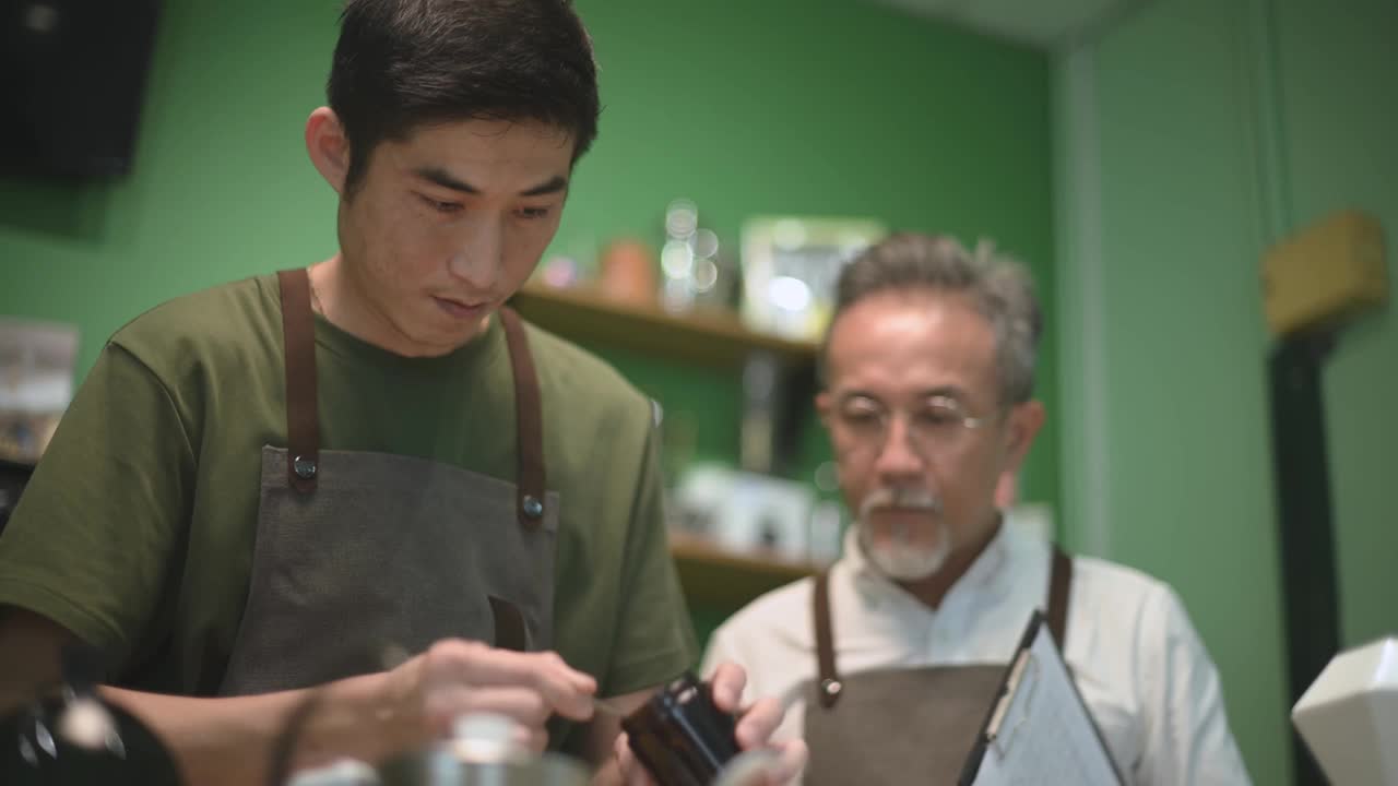 亚洲华人男咖啡师咖啡店老板正在和他的员工进行冷煮咖啡点滴培训视频下载