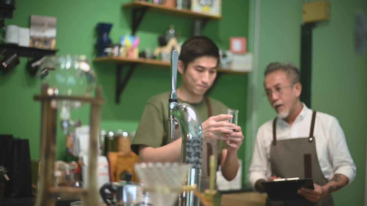 亚洲华人男咖啡师咖啡店老板正在和他的员工进行冷煮咖啡点滴培训视频素材