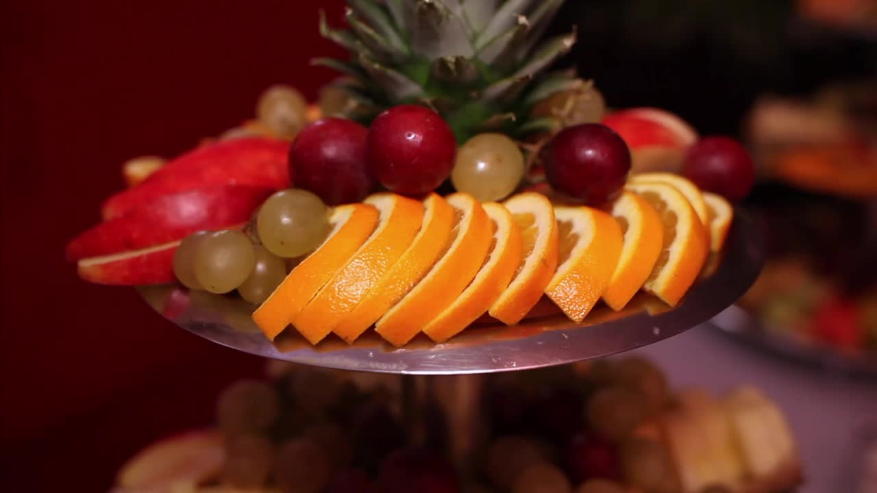 混合水果排列在多层托盘上。展示的水果包括葡萄、西瓜、菠萝、甜瓜、酸橙等视频下载