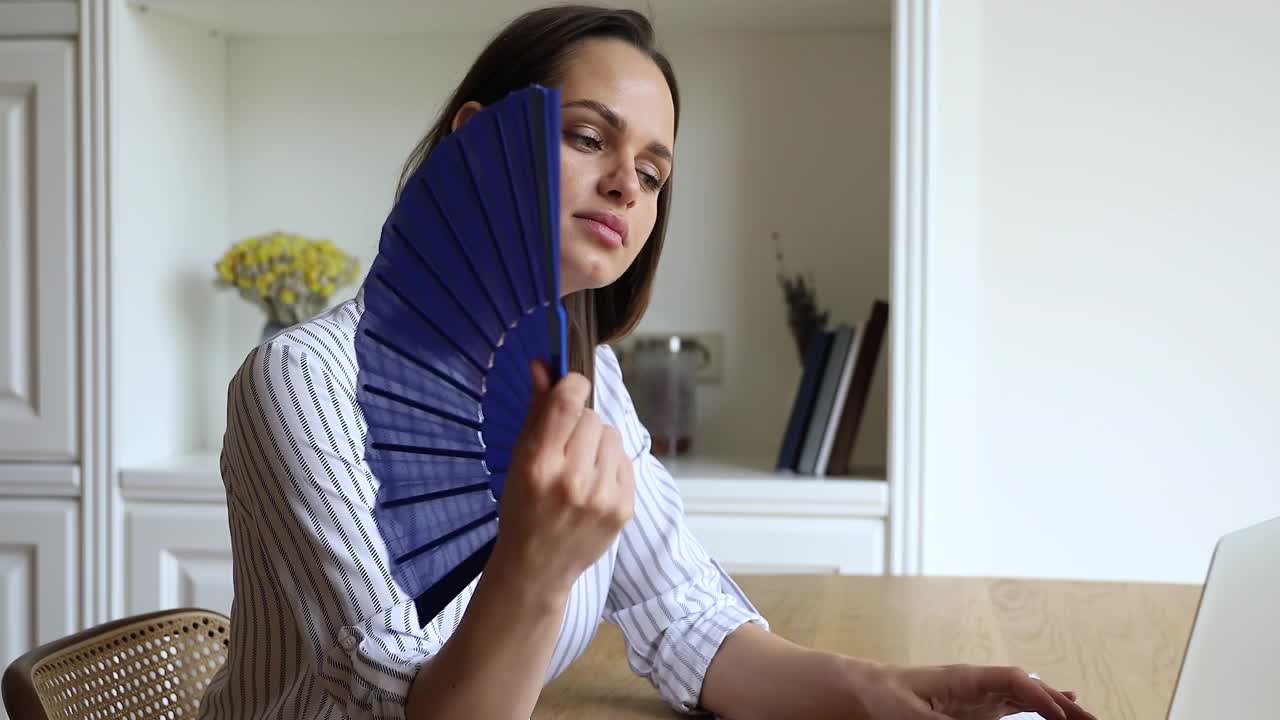 炎炎夏日，一名过热的女子用扇子给自己降温视频下载
