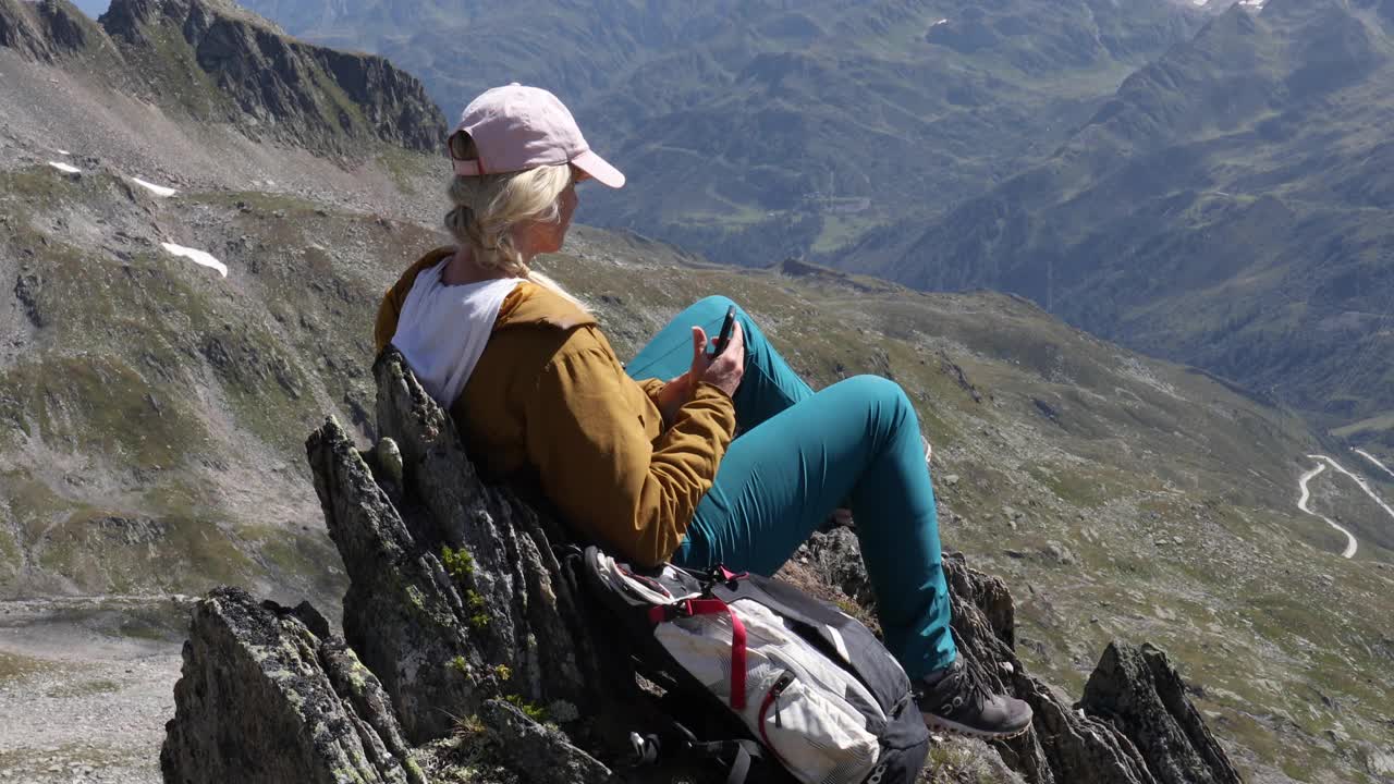 女徒步旅行者在山顶放松，山峰下面视频下载