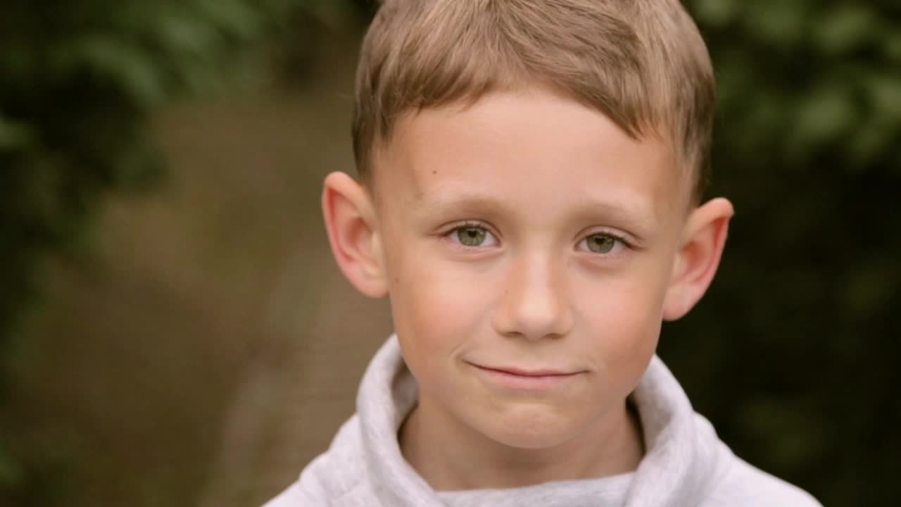 一个小男孩微笑着对着镜头摆姿势视频下载
