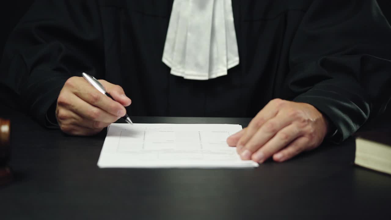 穿着黑色长袍的男法官在签署文件，诉讼结束，正义视频下载