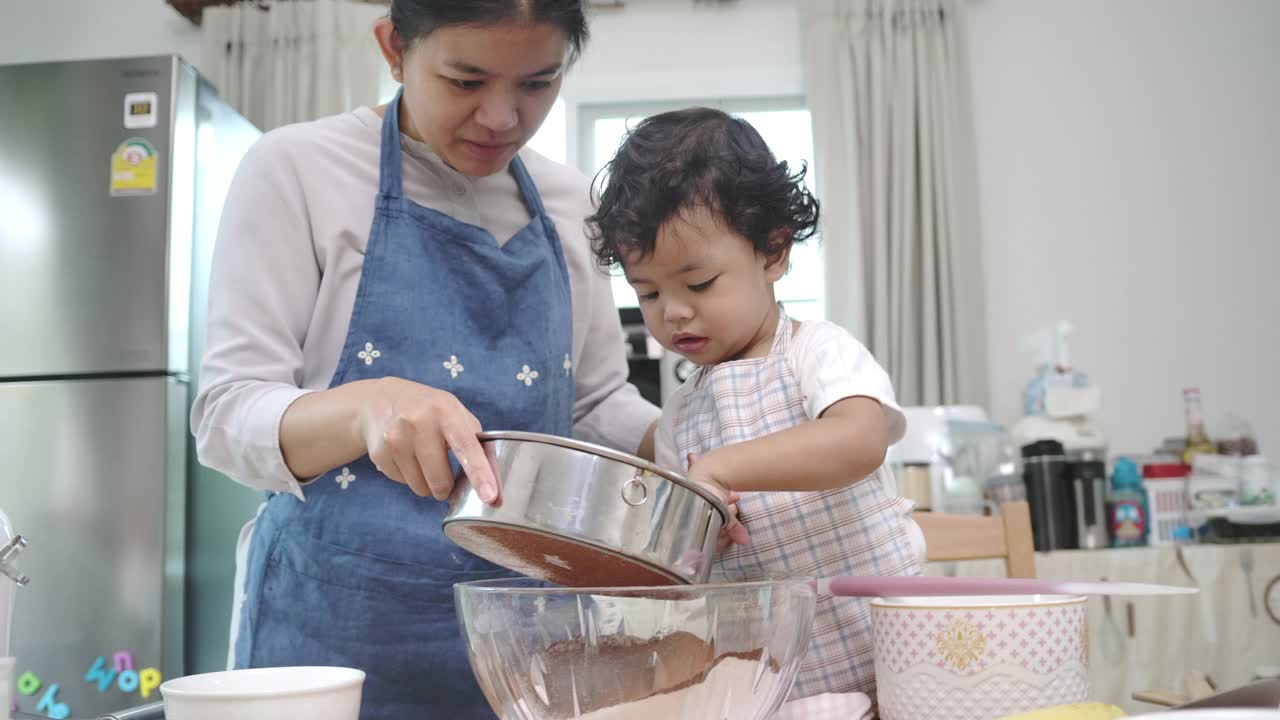 母亲和儿子一起做纸杯蛋糕。视频下载