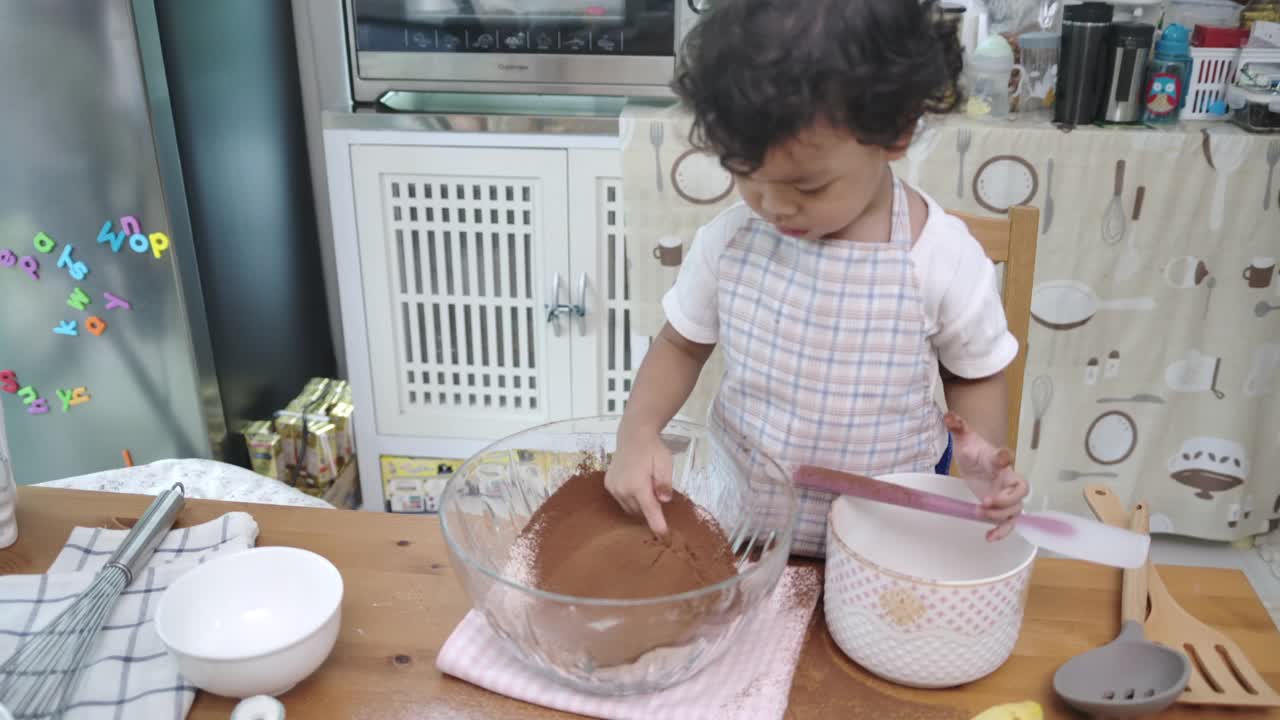 母亲和儿子一起做纸杯蛋糕。视频下载