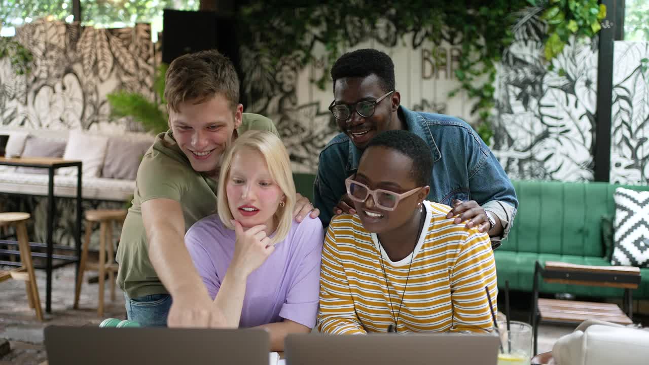 一群多种族的朋友一起看着笔记本电脑，大笑不止视频素材