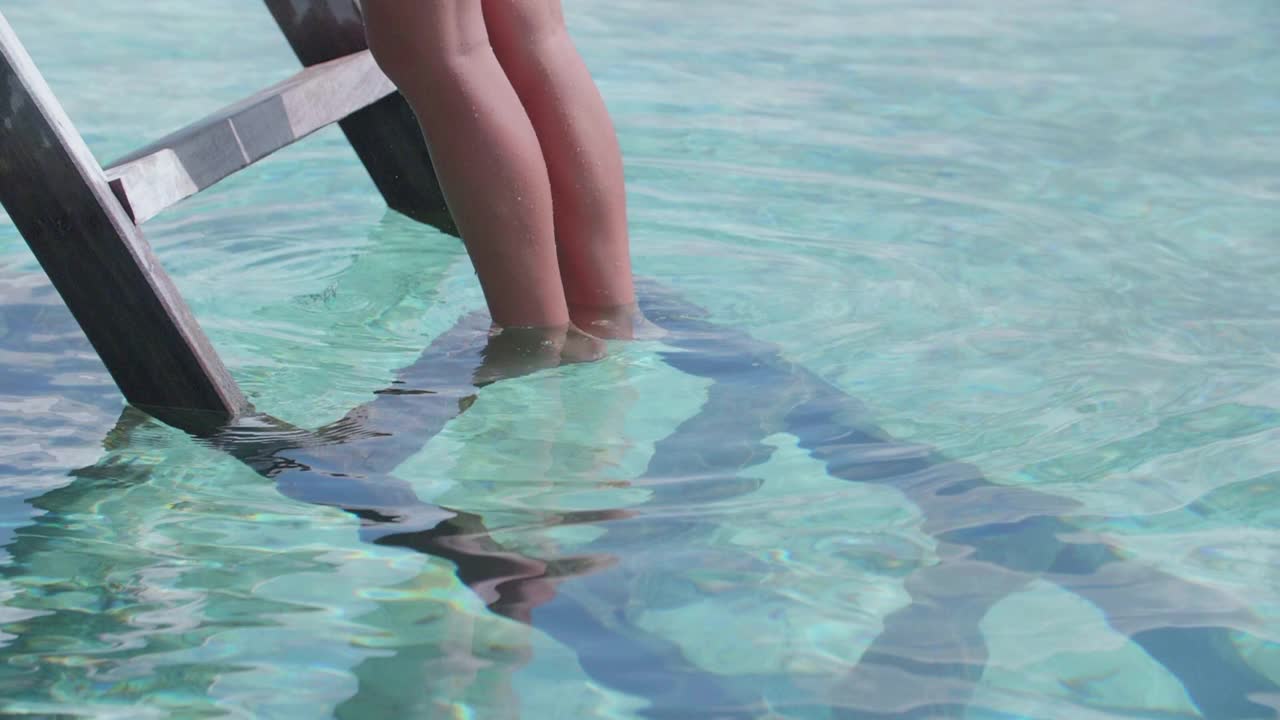 比基尼泳装穿着泳装的女子在热带岛屿度假酒店爬梯子。——慢动作视频素材