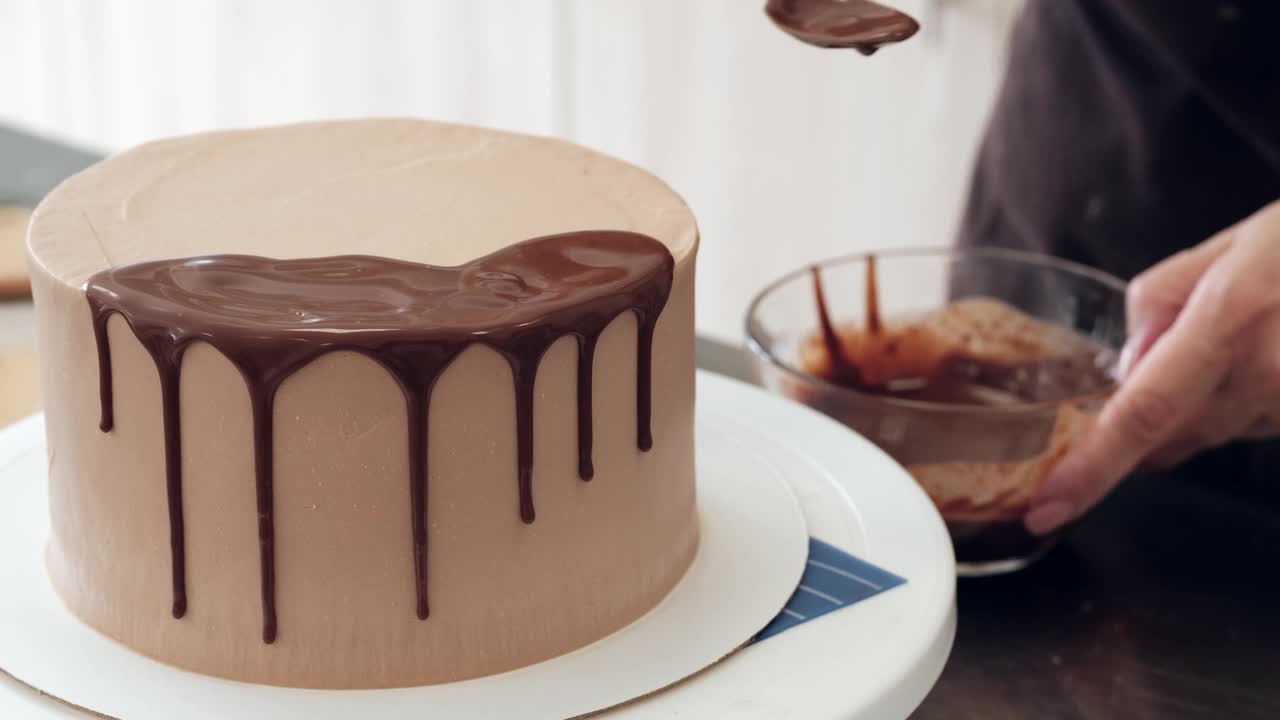 女糕点厨师装饰巧克力蛋糕和滴液体巧克力，特写。缓慢的运动。蛋糕制作过程。视频下载