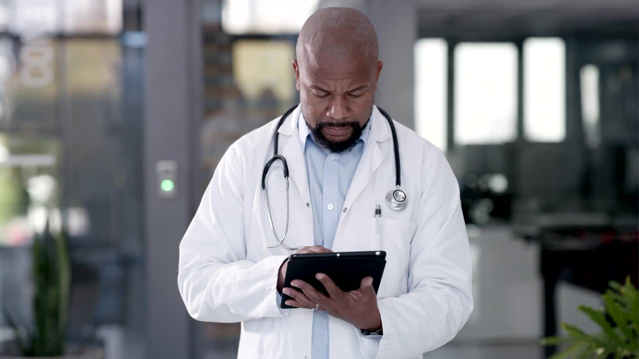 一段4k视频记录了一位微笑的医生在工作时用电子平板电脑检查医疗病例的过程视频素材