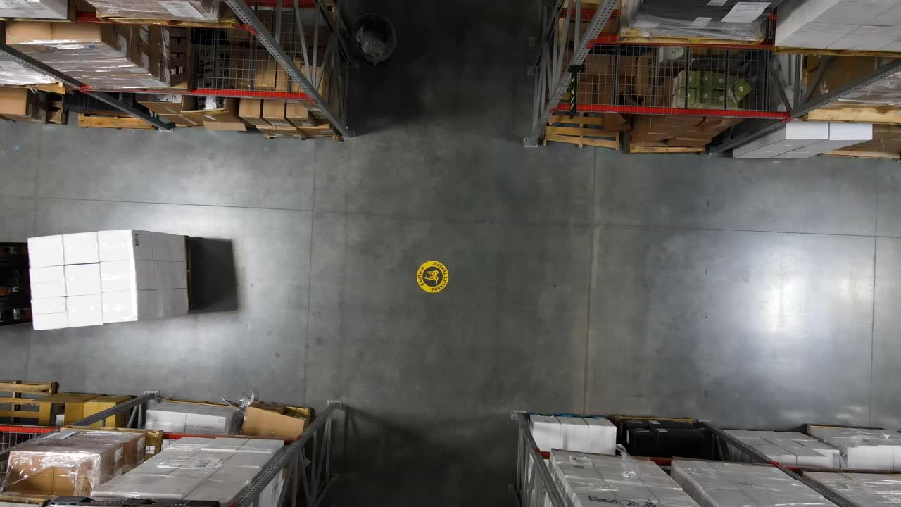 仓库工人用叉车在仓库走道角落搬运货物的高空照片视频素材