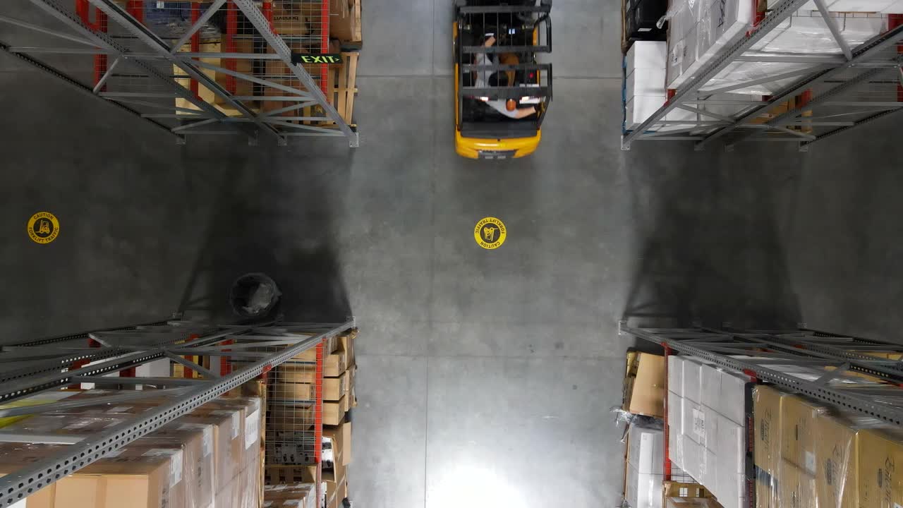 仓库工人在仓库用叉车搬运货物托盘的高空照片视频素材