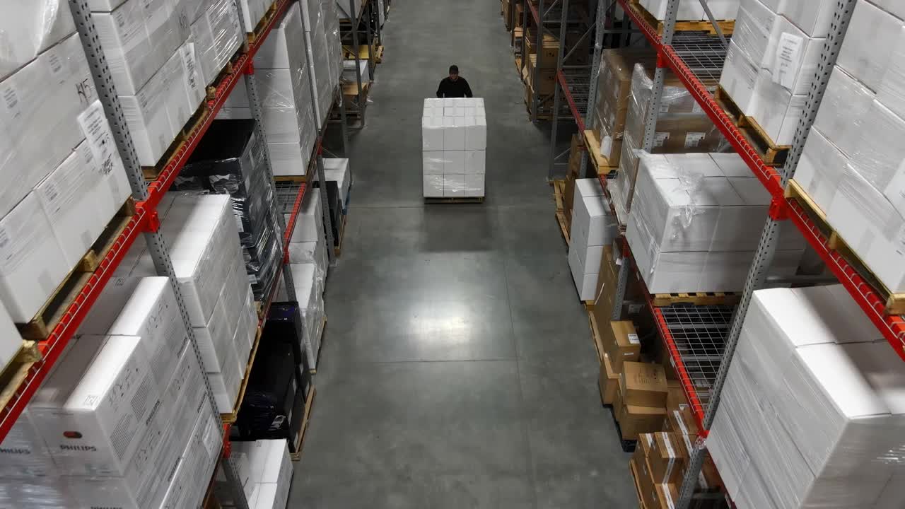 仓库工人用托盘千斤顶搬运货物托盘的高空高角度摄影视频素材