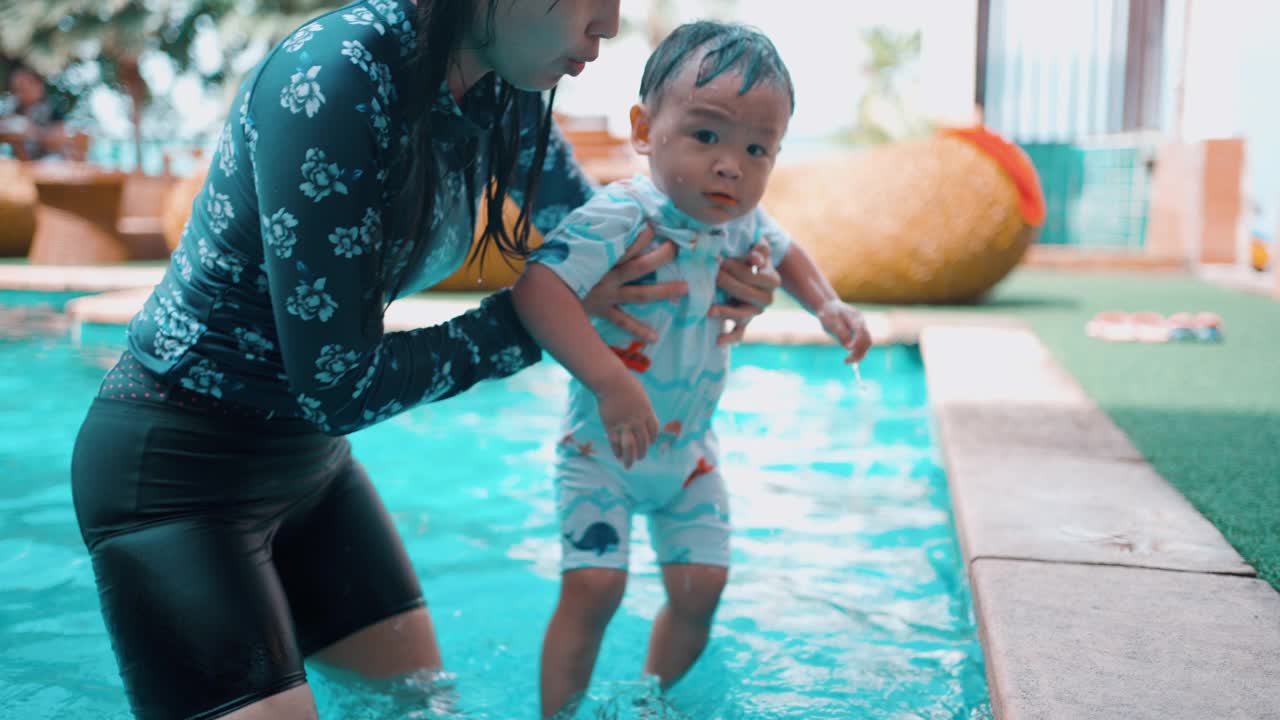 快乐的妈妈和儿子在游泳池里玩耍视频素材
