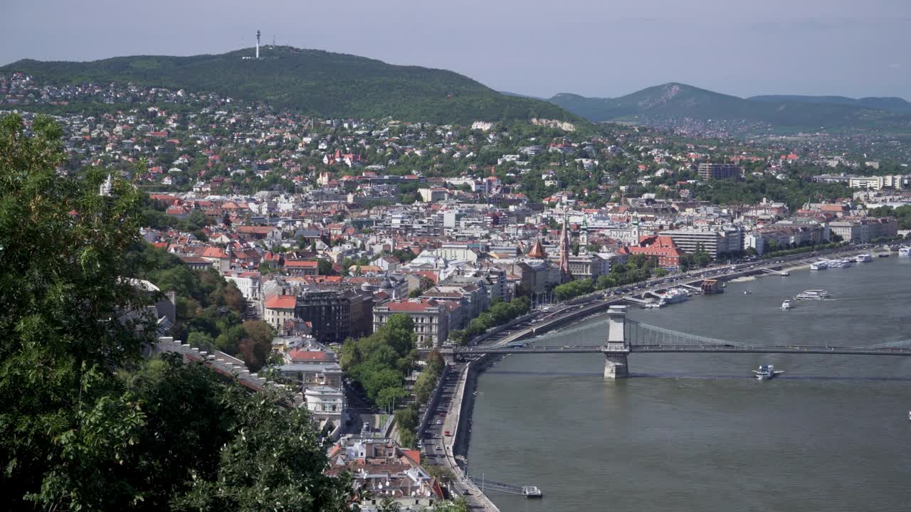 布达佩斯城市景观在匈牙利议会和铁链桥之间，Széchenyi铁链桥与一个繁忙的周末，与游客，交通堵塞和交通在布达佩斯，匈牙利，拍摄高角度的侧景，视频素材