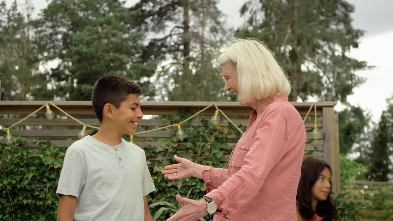 奶奶笑着抱着孙子，在后院用手量身高视频下载