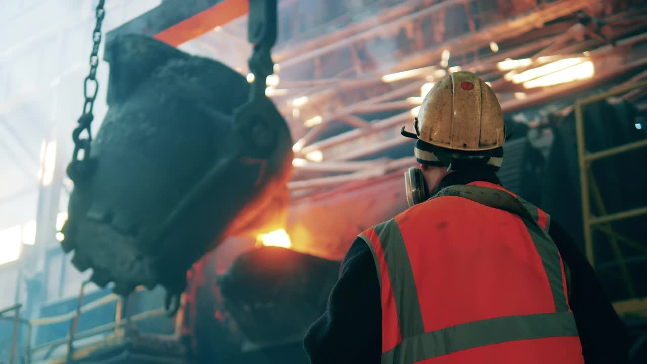 在观察铸钢过程中，冶金学家从后面拍摄视频素材