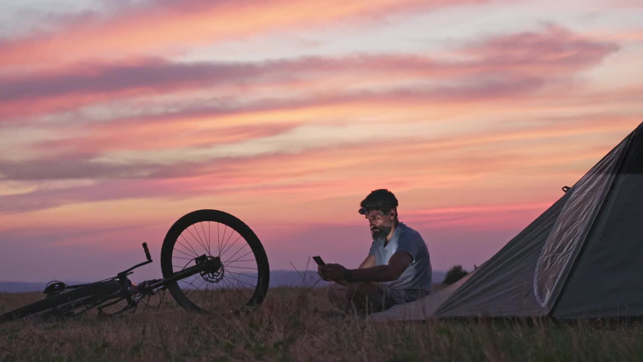 在日落时骑山地自行车和露营。视频下载