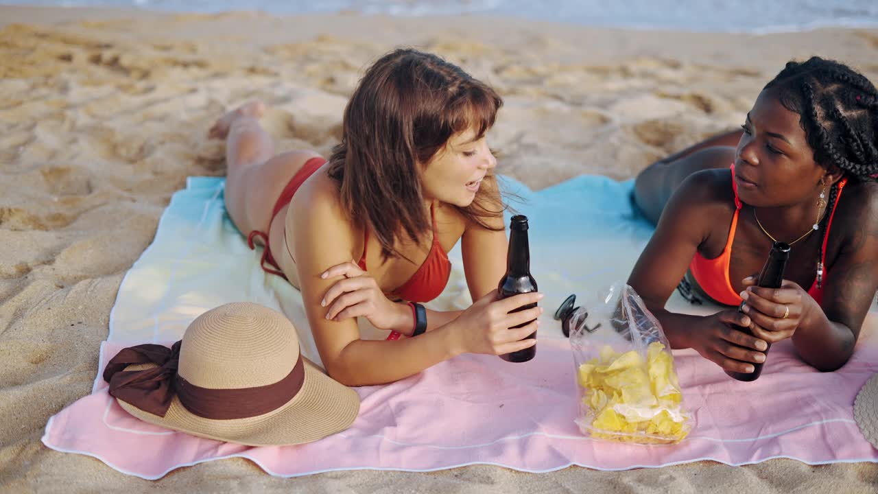 两个可爱的不同种族的女孩在海滩上晒太阳视频下载