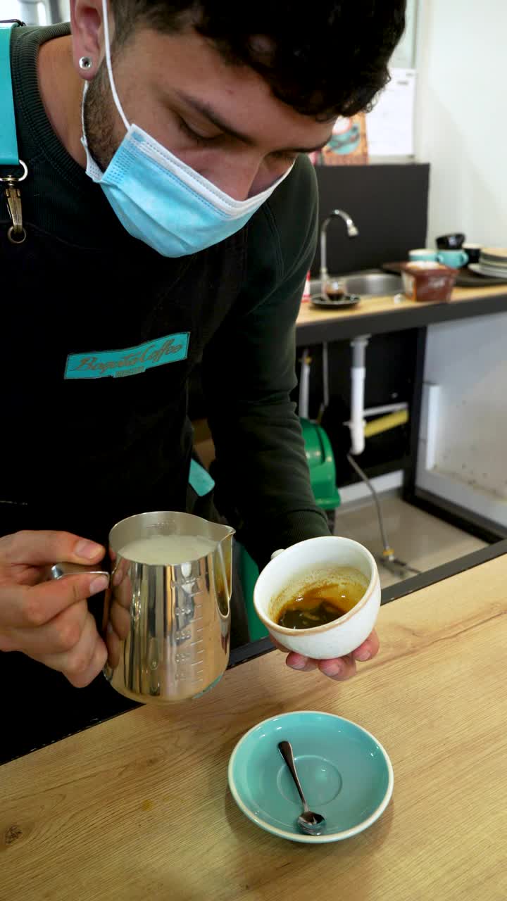 拉丁男子咖啡店员工设计咖啡杯上的花视频素材