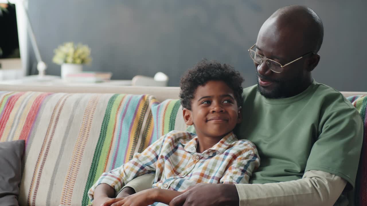 快乐的非洲父亲和儿子在家里沙发上的肖像视频素材