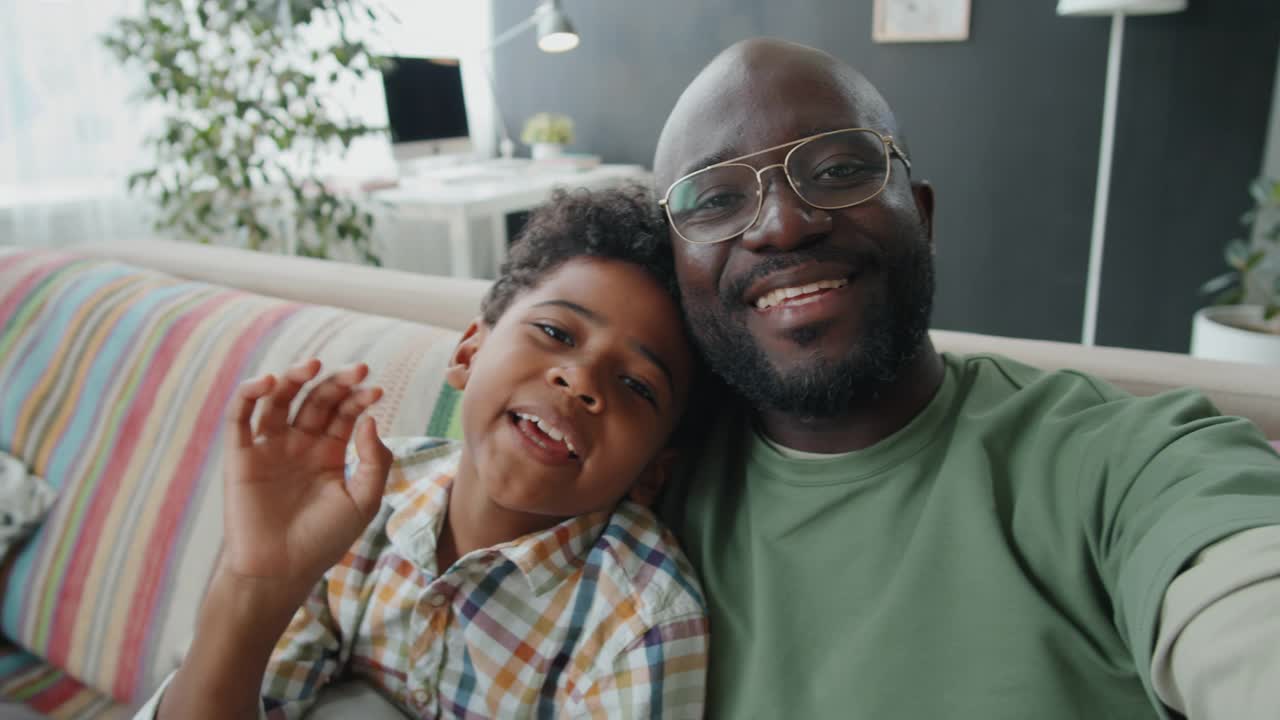 欢快的非洲爸爸和小儿子在视频通话中聊天视频素材
