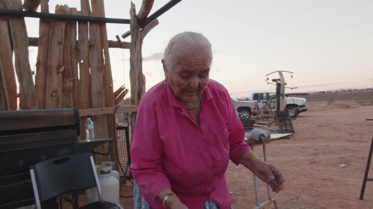 上了年纪的纳瓦霍妇女在她新编织的篮子上涂上松树树沥青，在室外的木炉子上加热，特写视频剪辑视频下载