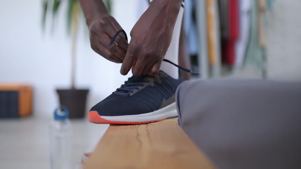 在家锻炼前，一个年轻人正在给运动鞋系鞋带视频下载