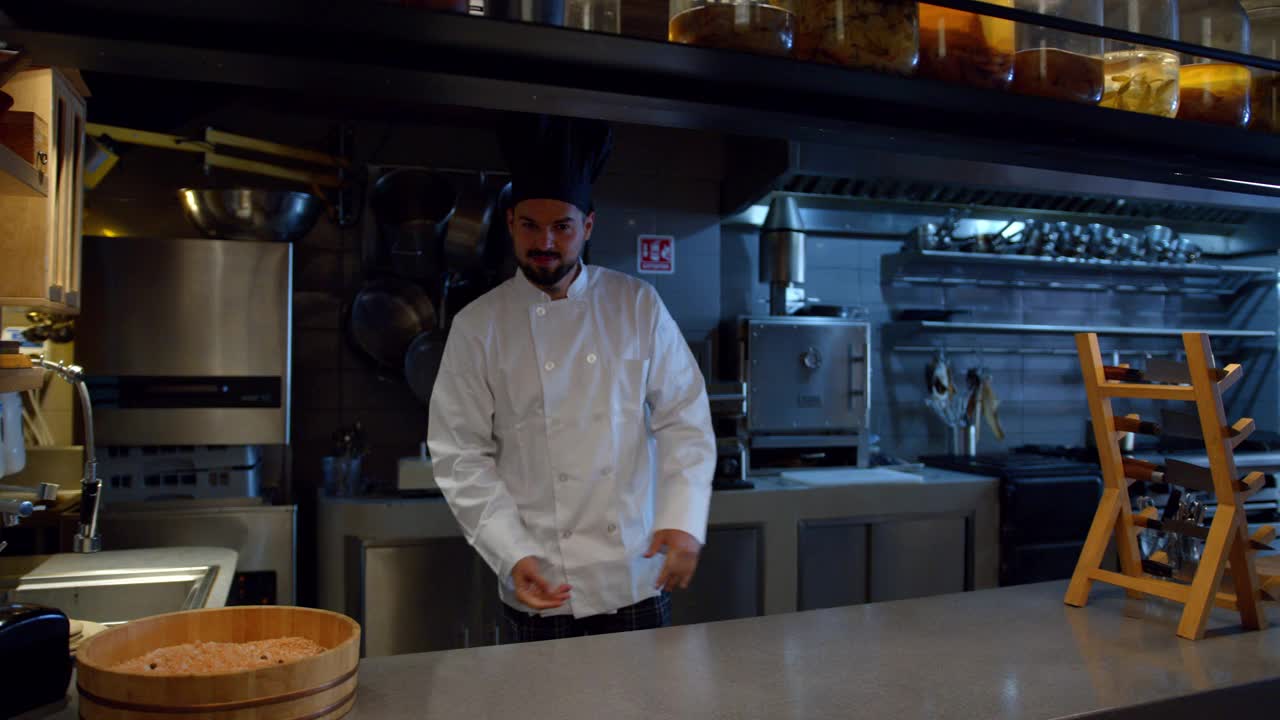 餐厅的厨师双手扶在厨房柜台上，对着镜头微笑视频素材